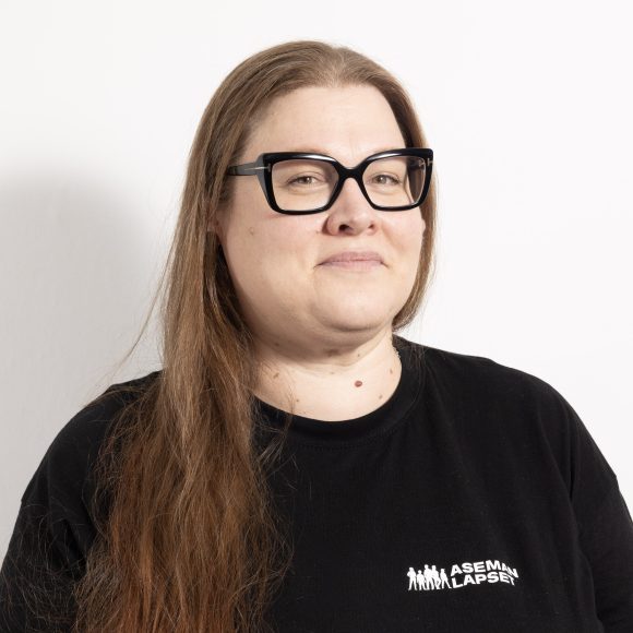 nainen pitkässä tukassa, mustissa silmälaseissa ja mustassa paidassa