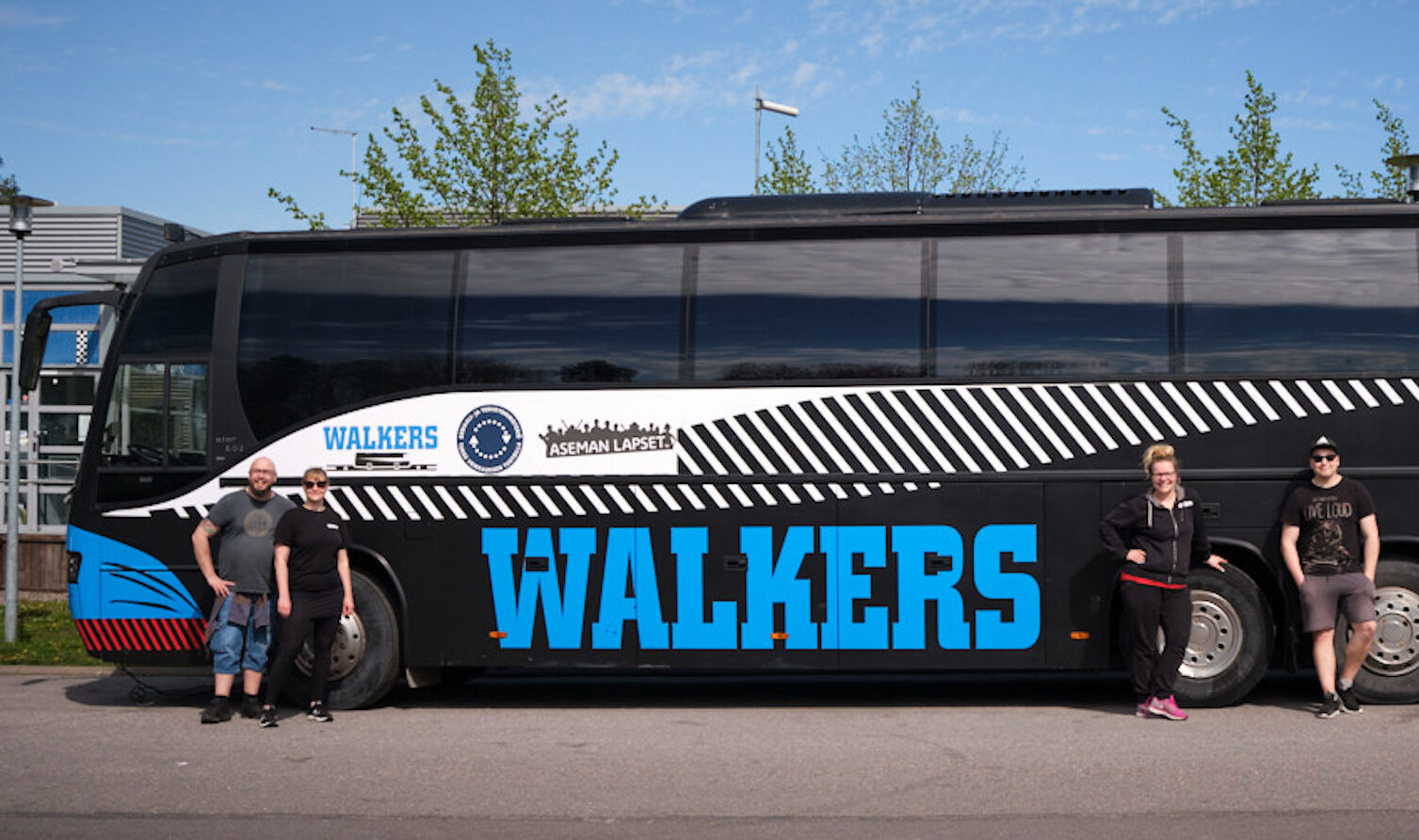 Walkers-bussi sivustapäin. Bussin edessä työntekijöitä seisomassa.