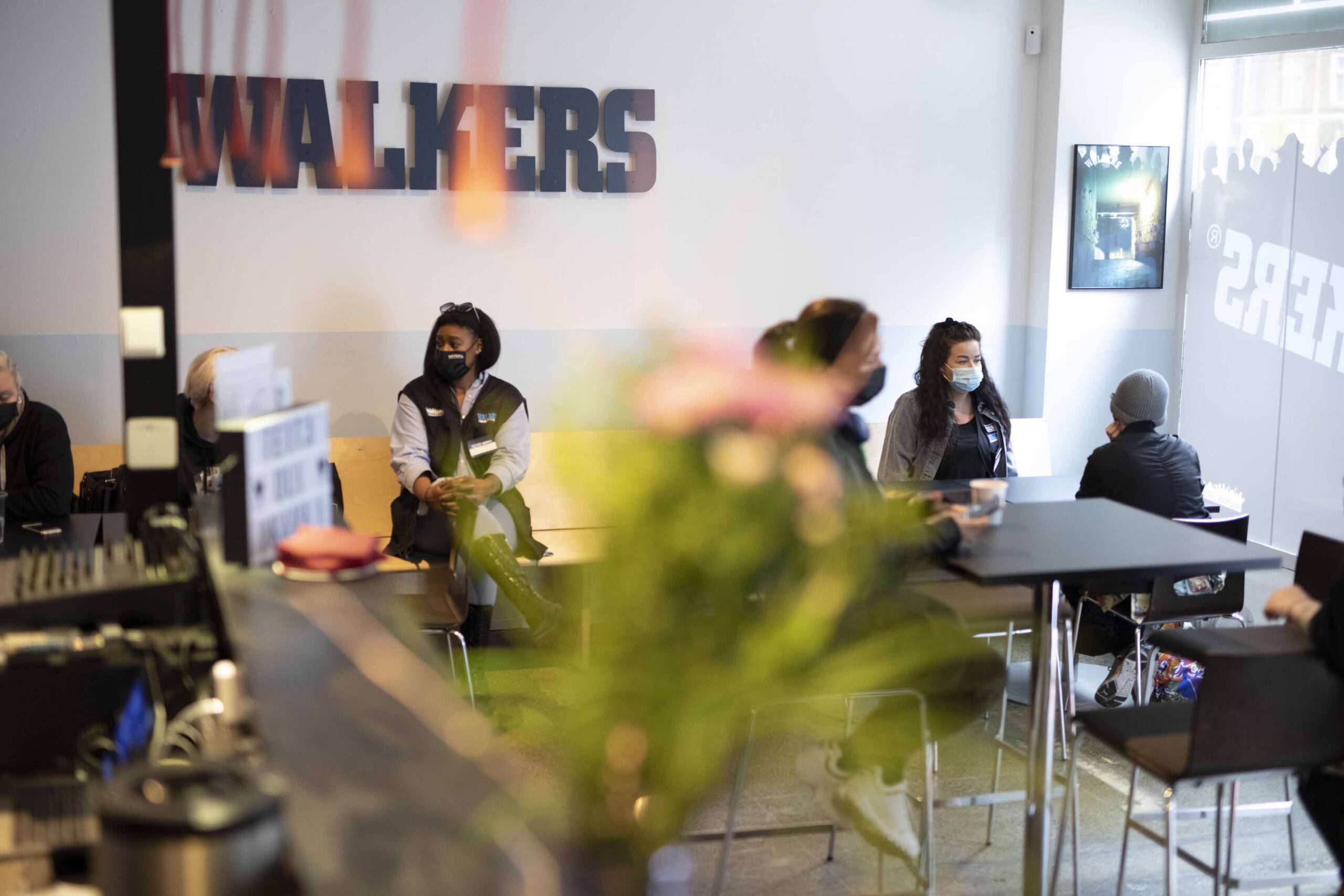 Ihmisiä istumassa kahvilassa, jonka seinällä lukee Walkers