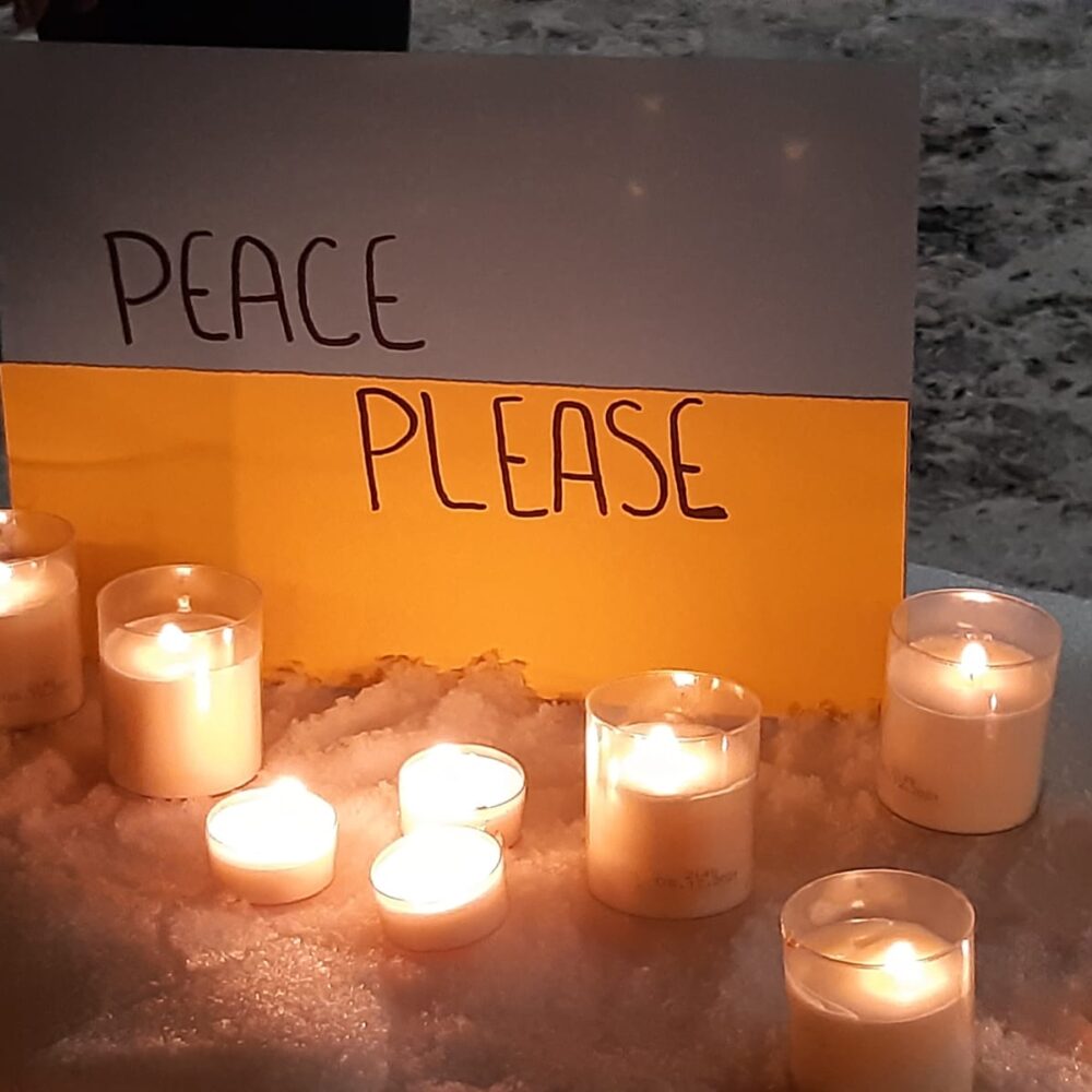 Palavia kynttilöitä taulun edessä jossa lukee Peace please.
