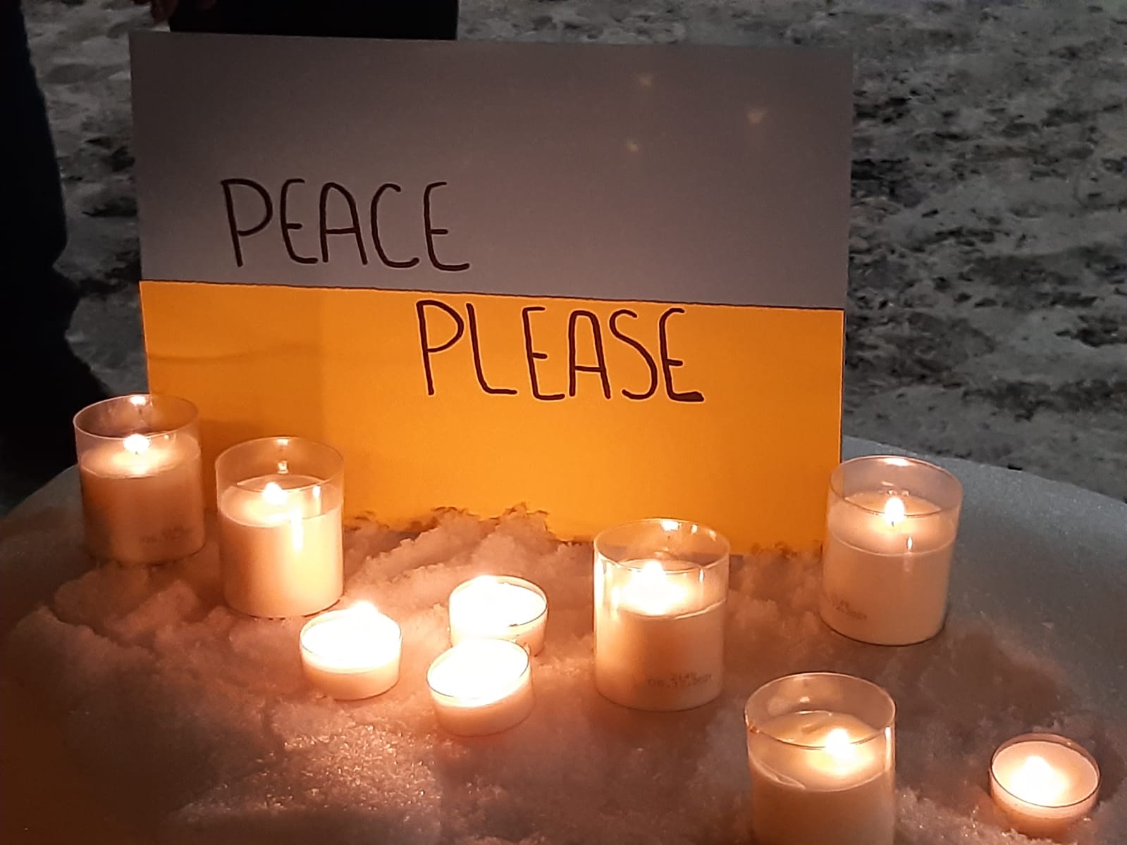 Palavia kynttilöitä taulun edessä jossa lukee Peace please.