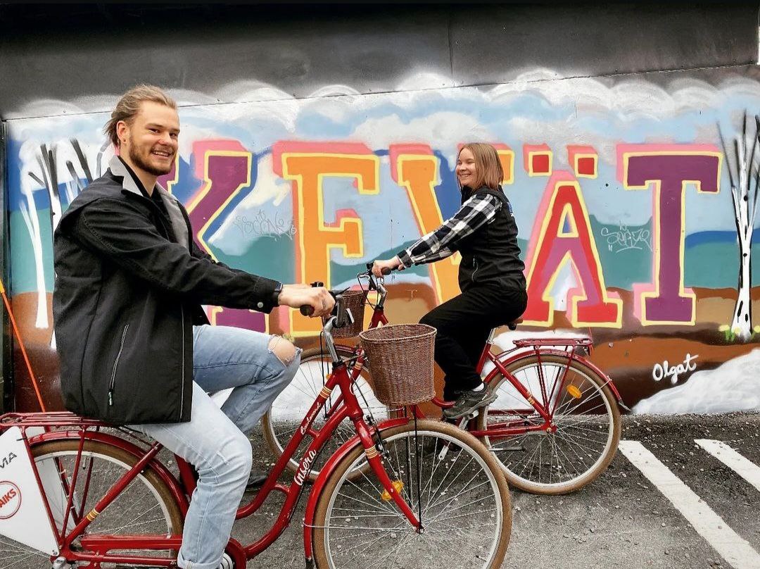 Kaksi pyöräilijää iloisena ajaa toistensa ohitse ilman pyöräilykypäriä