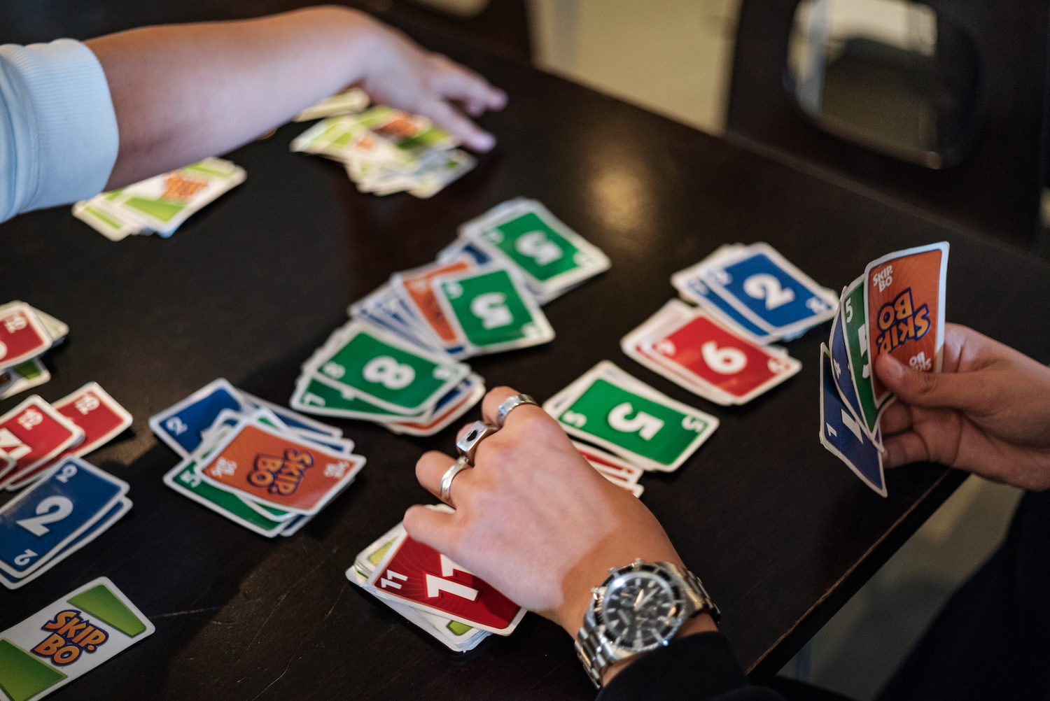 Kaksi henkilöä pelaa korttipeliä, korteissa lukee skippo.