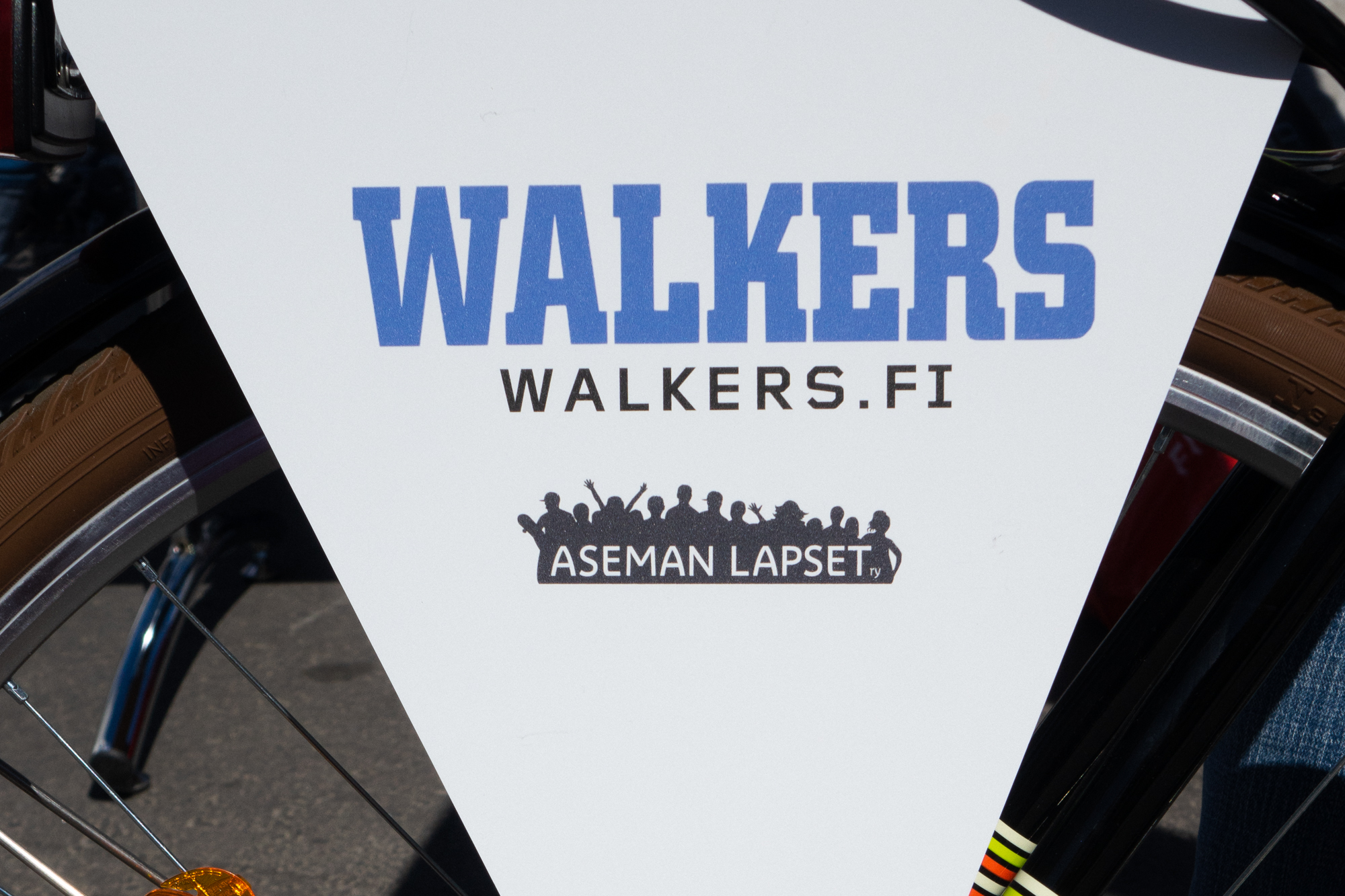 Polkupyörässä viiri, jossa lukee Walkers.fi ja Aseman Lapset ry:n logo