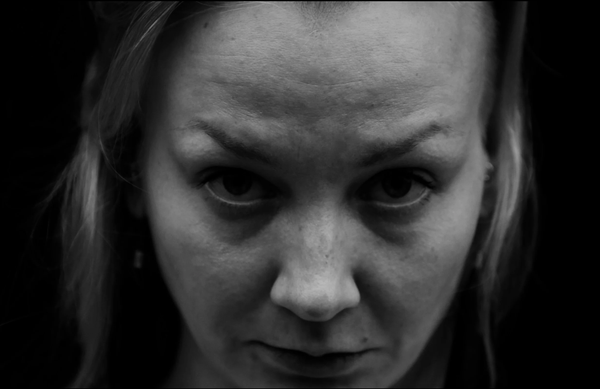 Mustavalkoinen lähikuva naisen otsasta ja kasvoista.