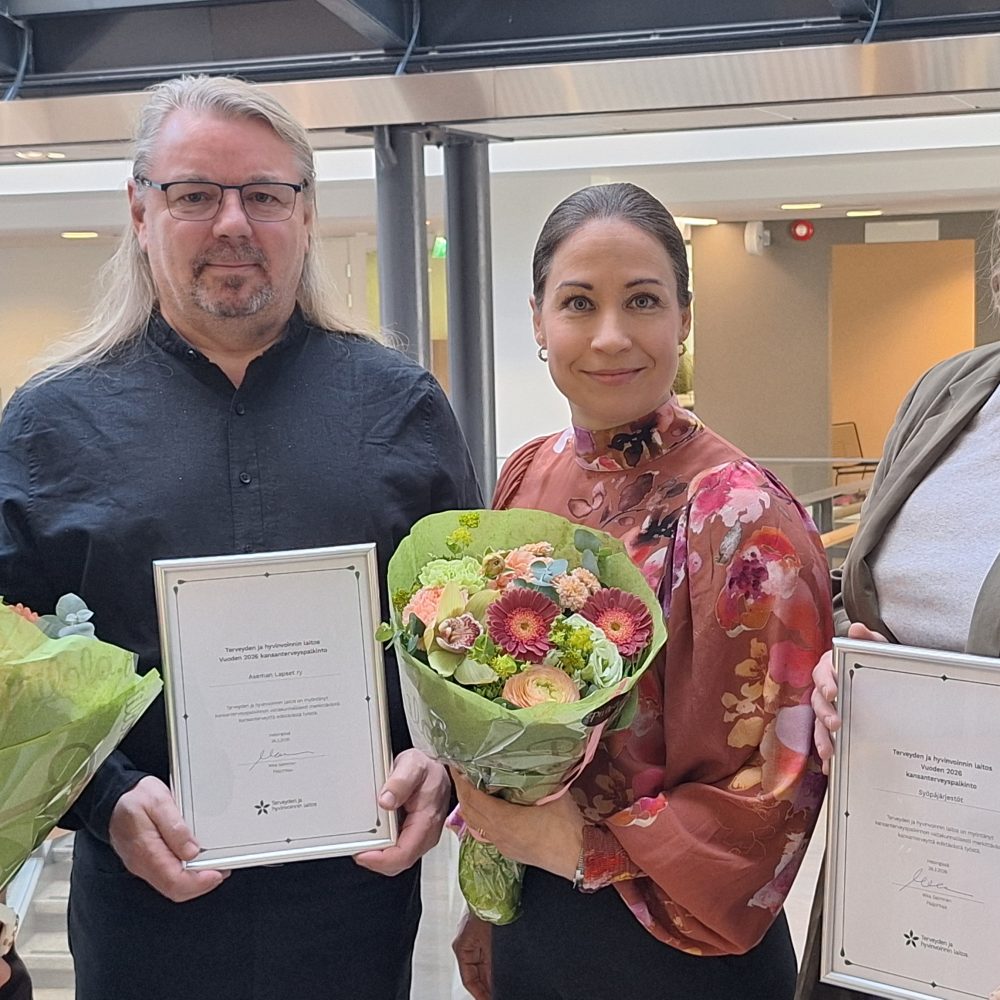 Neljä palkittua aikuista kukkien ja kunniakirjojen kanssa