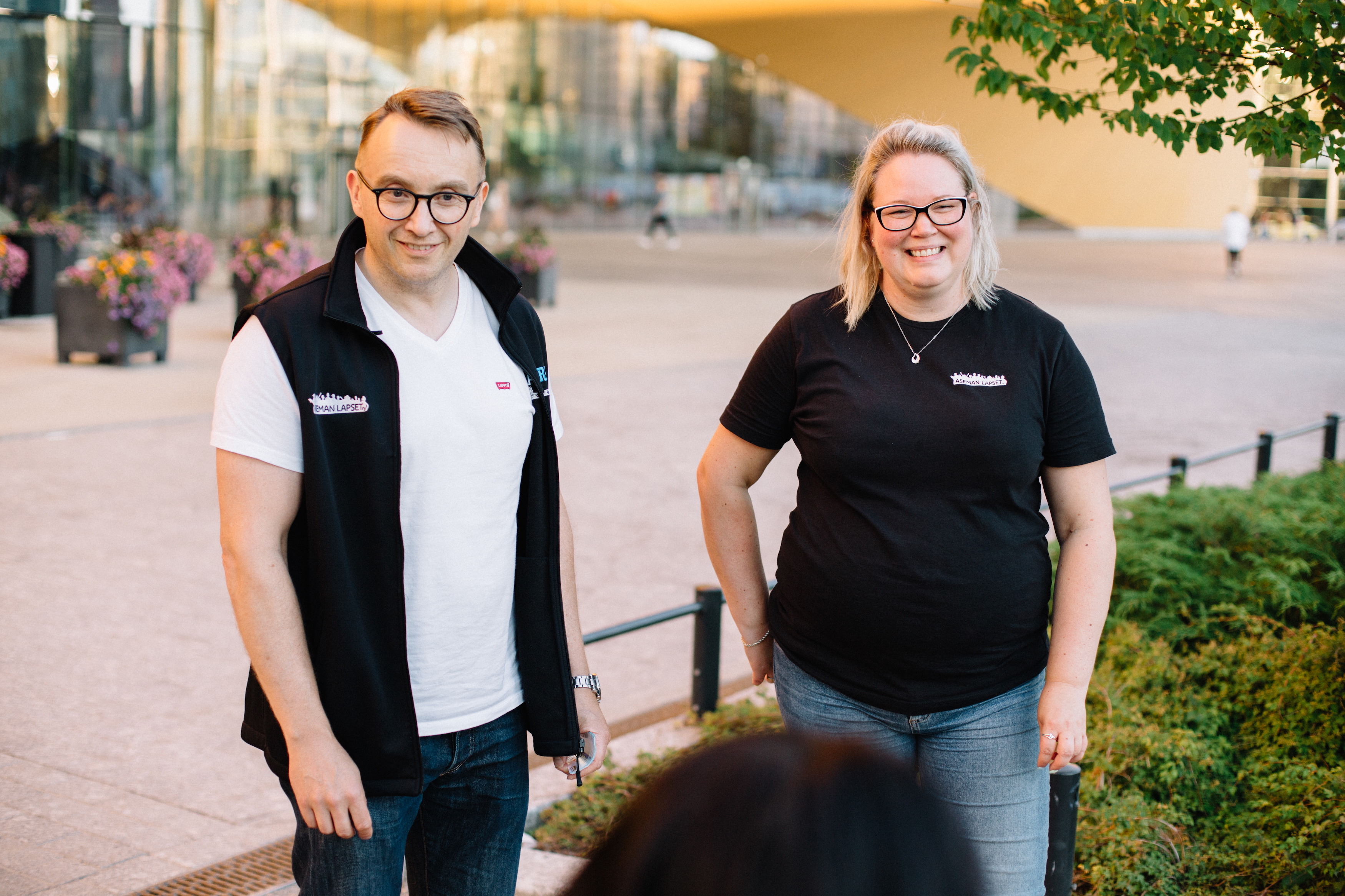 Nuorisotyöntekijä ja vapaaehtoinen aikuinen juttelevat nuoren kanssa Oodin edustalla.